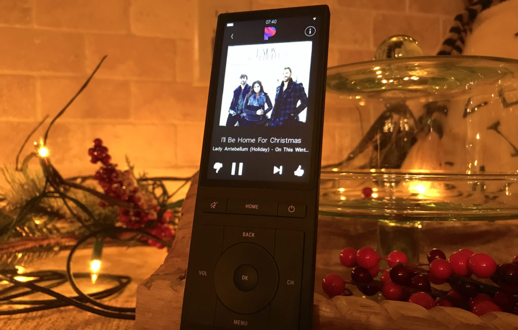 Music playing on a touchscreen remote surrounded by holiday decorations