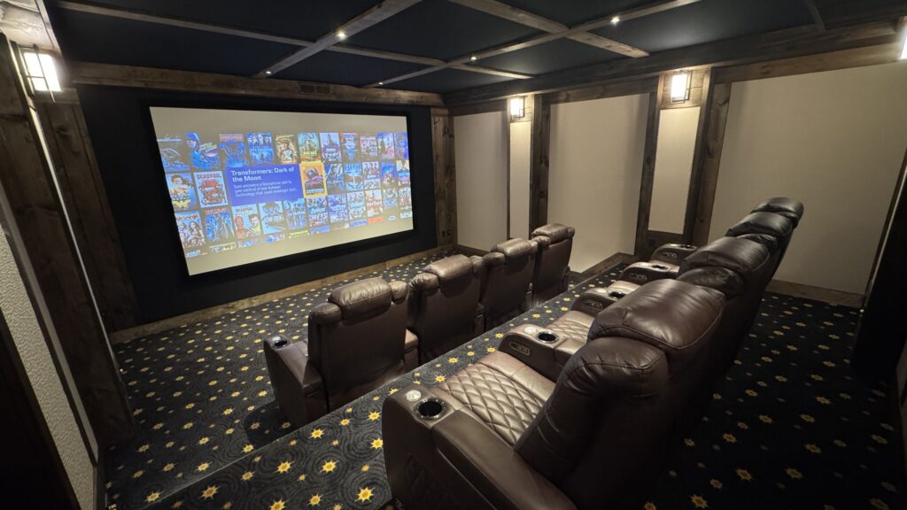 Dedicated home theater with tiered leather recliners, timber beams and a large screen